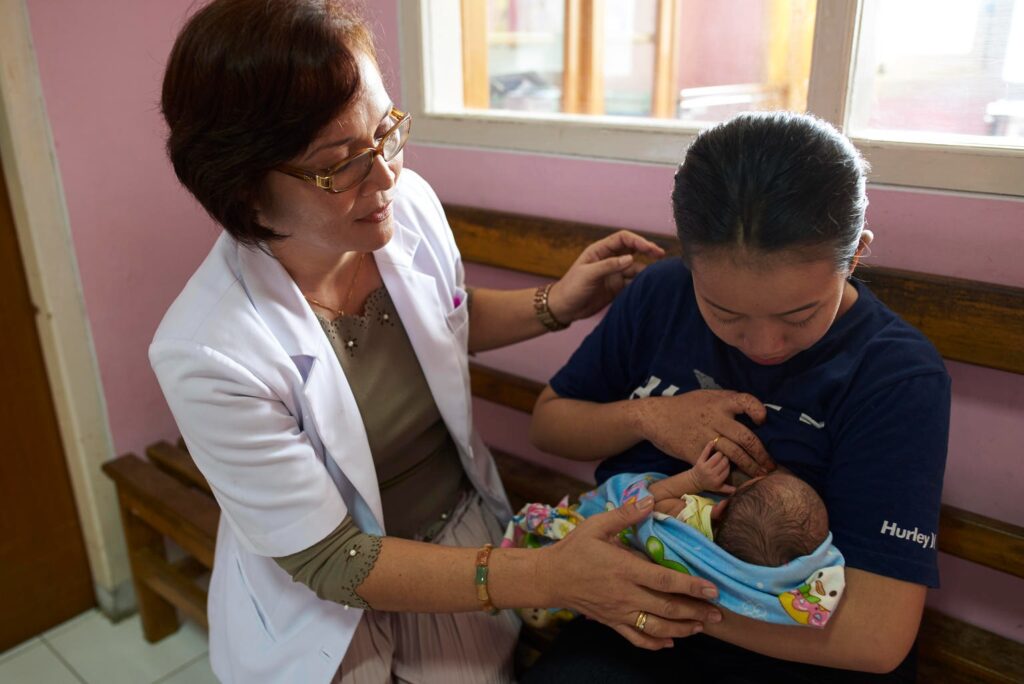 Pada 13 Juli 2018 di Indonesia, Dr. Marito memperlihatkan kepada seorang ibu cara menggendong bayi saat menyusui di Unit Neonatal Rumah Sakit Umum Yowari, di Kota Sentani, Kabupaten Jayapura, Provinsi Papua. ©️ UNICEF/UN0248689/Noorani